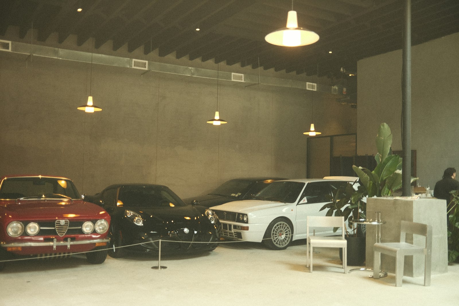 Cars displayed in a showroom under hanging lights