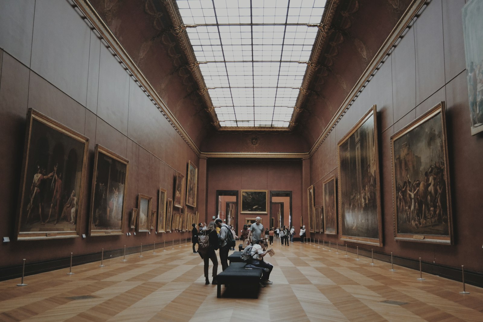 Visitors walking along a gallery corridor looking at paintings